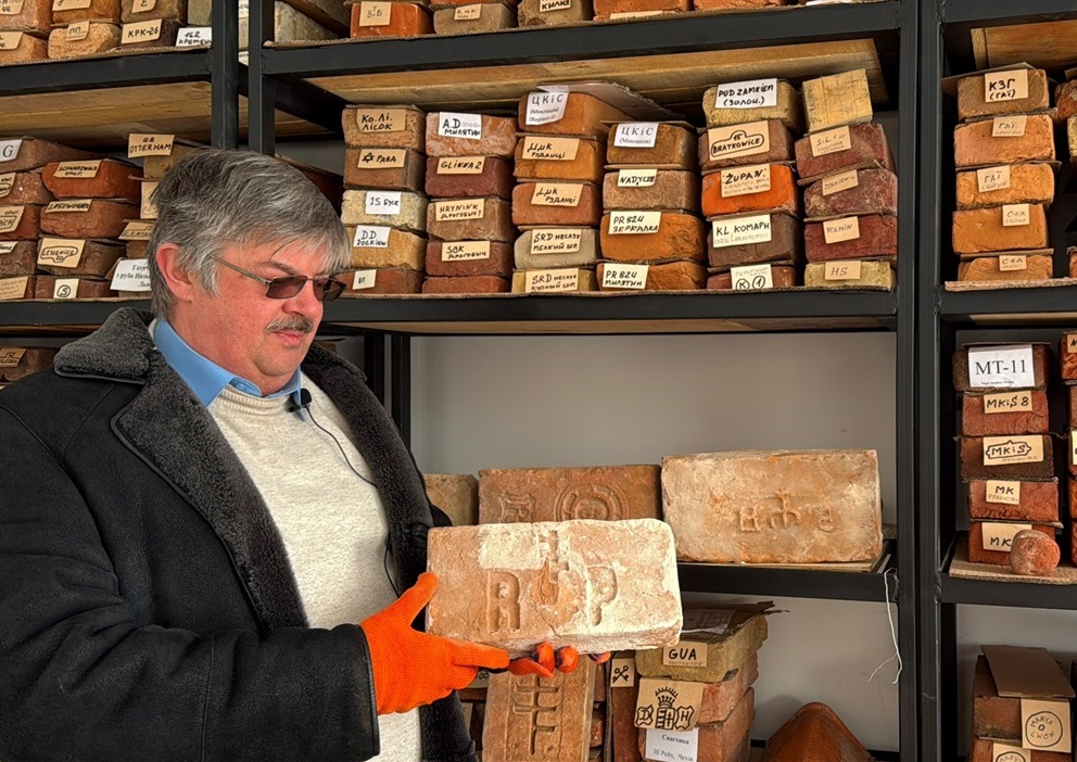 Олександр Волков показує цеглину з гербом графа Романа Потоцького