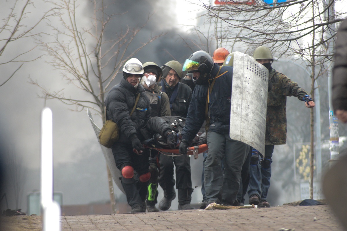 Учасники подій у Києві переносять пораненого з поля бою. 20 лютого 2014 року