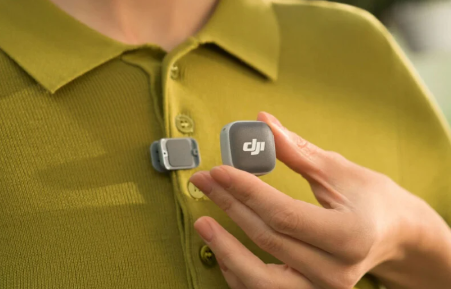 Трансмітер DJI Mic Mini 2 закріплюють магнітом на трикотажному поло гірчичного кольору, зворотна магнітна пластина вже зафіксована з внутрішнього боку тканини.